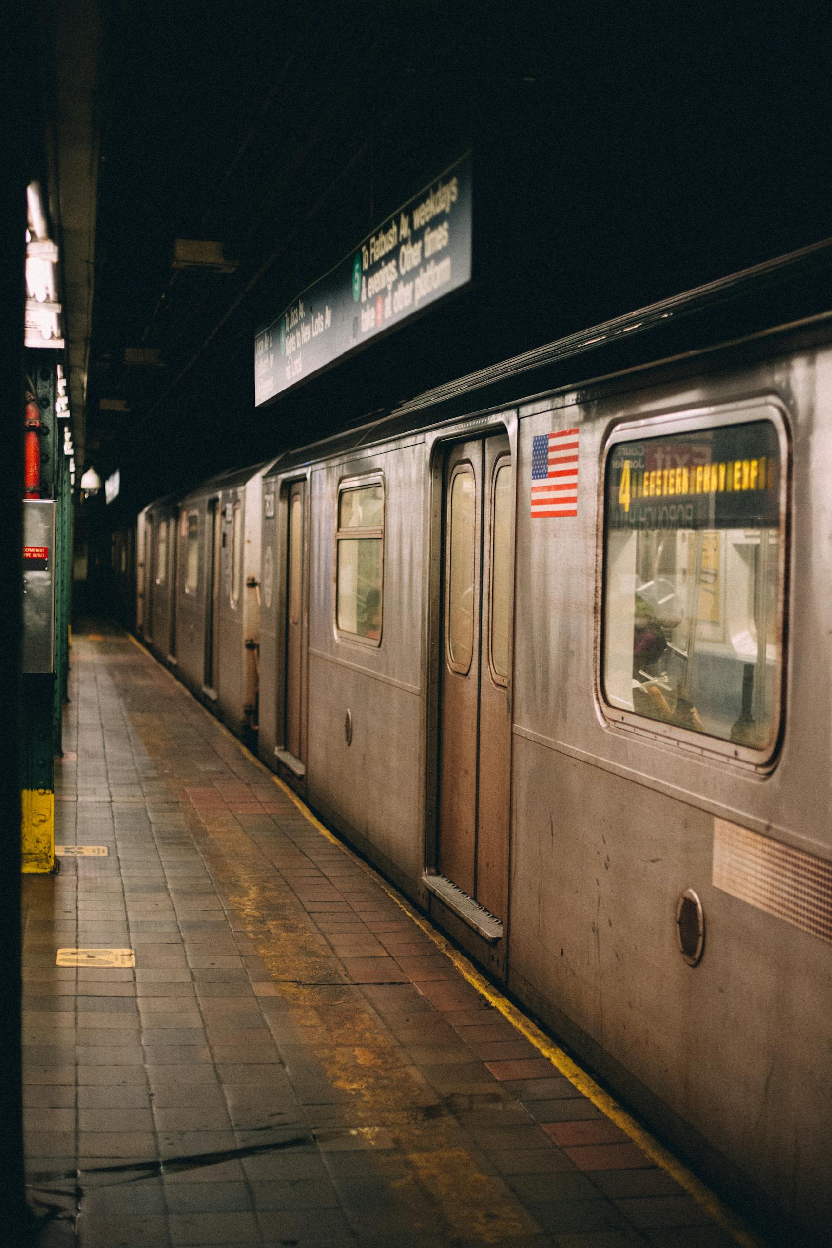 A New York City subway train at an underground station showcasing urban transportation.