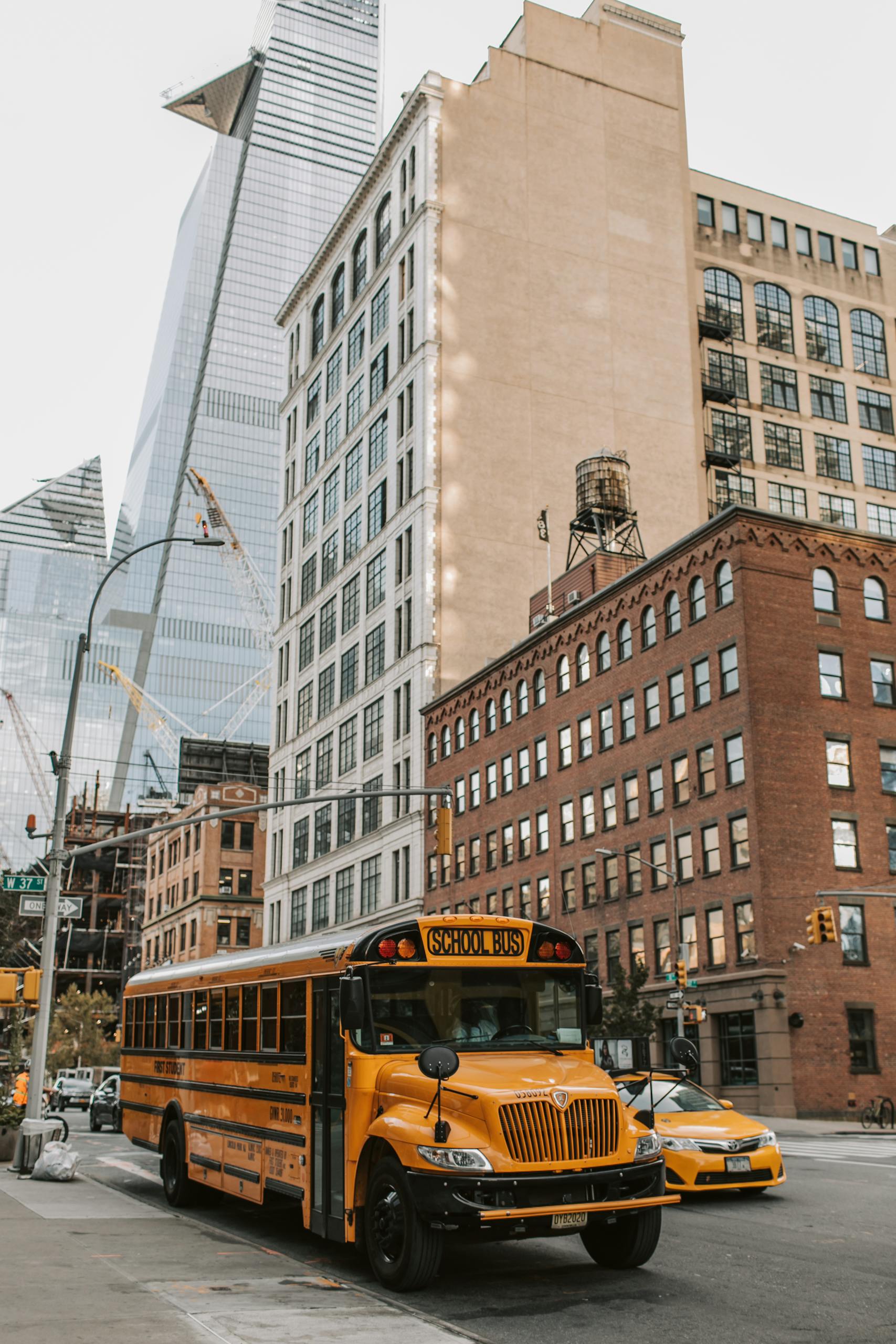 Yellow school bus and buildings in New York City, showcasing urban life and architecture.